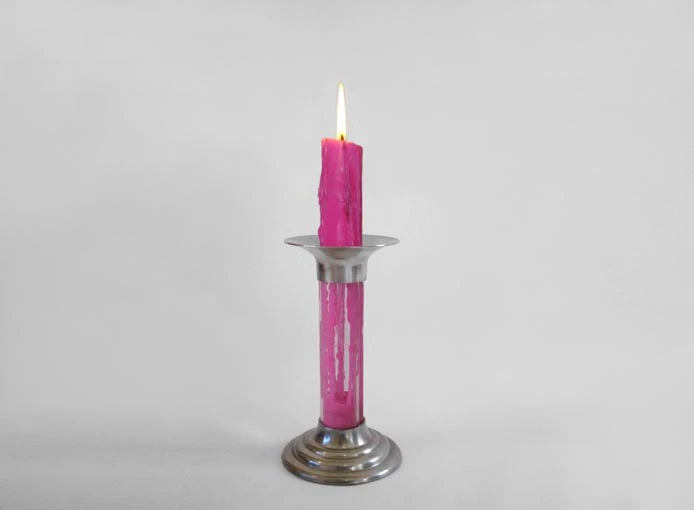 A wick hangs down through the center of the lower well, allowing the used wax to form into a new candle