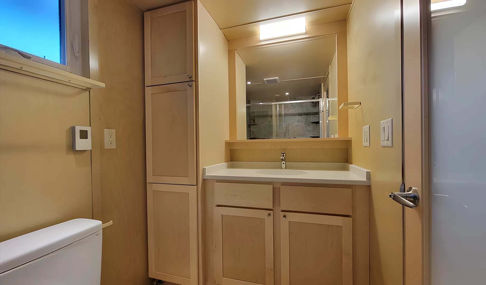 The Ultimate tiny house's bathroom includes a shower, vanity sink, and flushing toilet