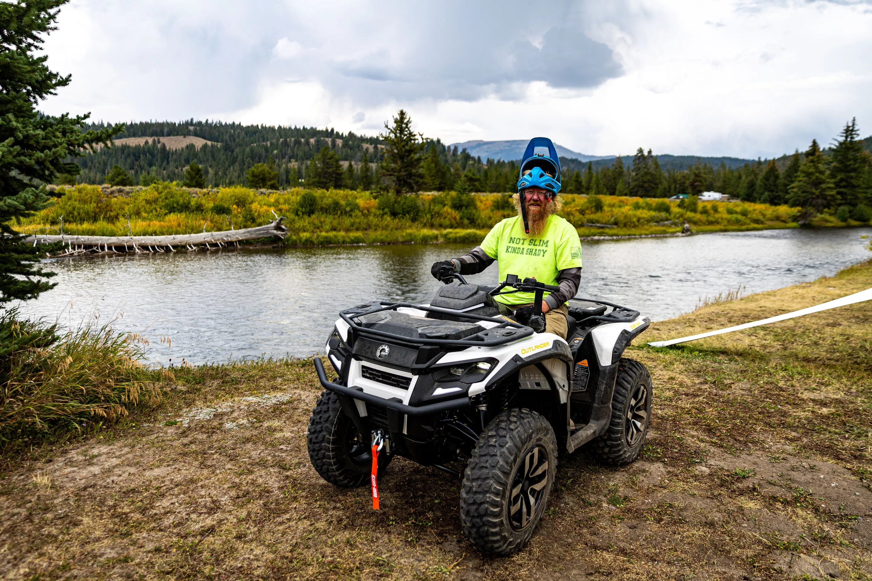 Mugging for the camera, the author sits on a Can-Am Outlander Electric at a river near Jackson Hole, Wyoming