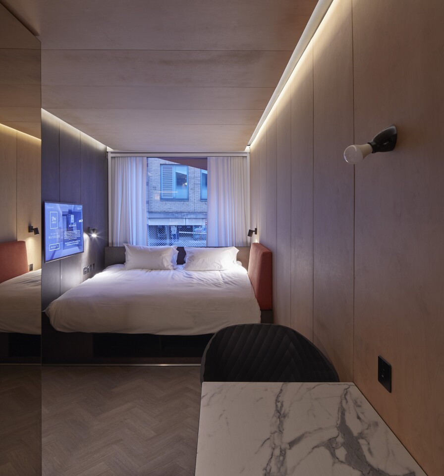 The Stow-Away Hotel's interiors include a bed, dining table, kitchenette and bathroom