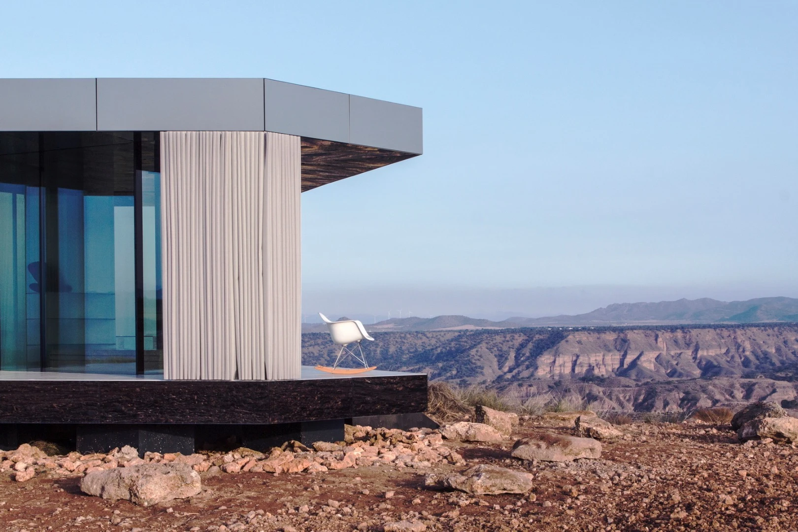 The Glass House features a shaded porch area with large curtains, enabling some shading and a little additional privacy