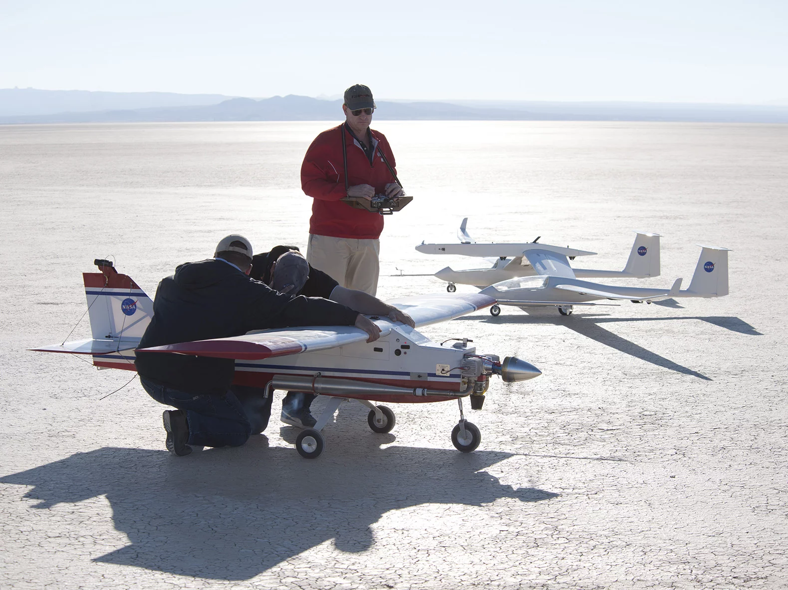 Small unmanned aircraft technician Derek Abramson and glider pilot Red Jensen, hold back the DROID tow plane while pilot Gerald Budd runs through some last minute checks (Photo: NASA / Tom Tschida)