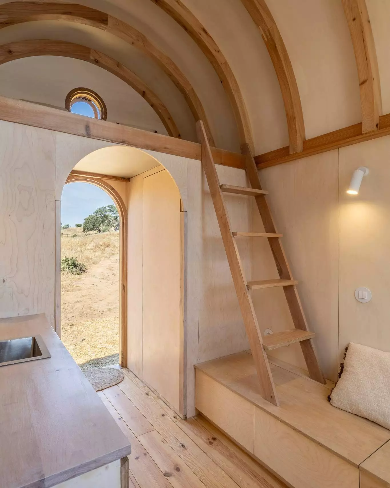 The Terra m1_Tiny House on Wheels' loft area is reached by wooden steps and looks suitable for use as a second bedroom or storage area