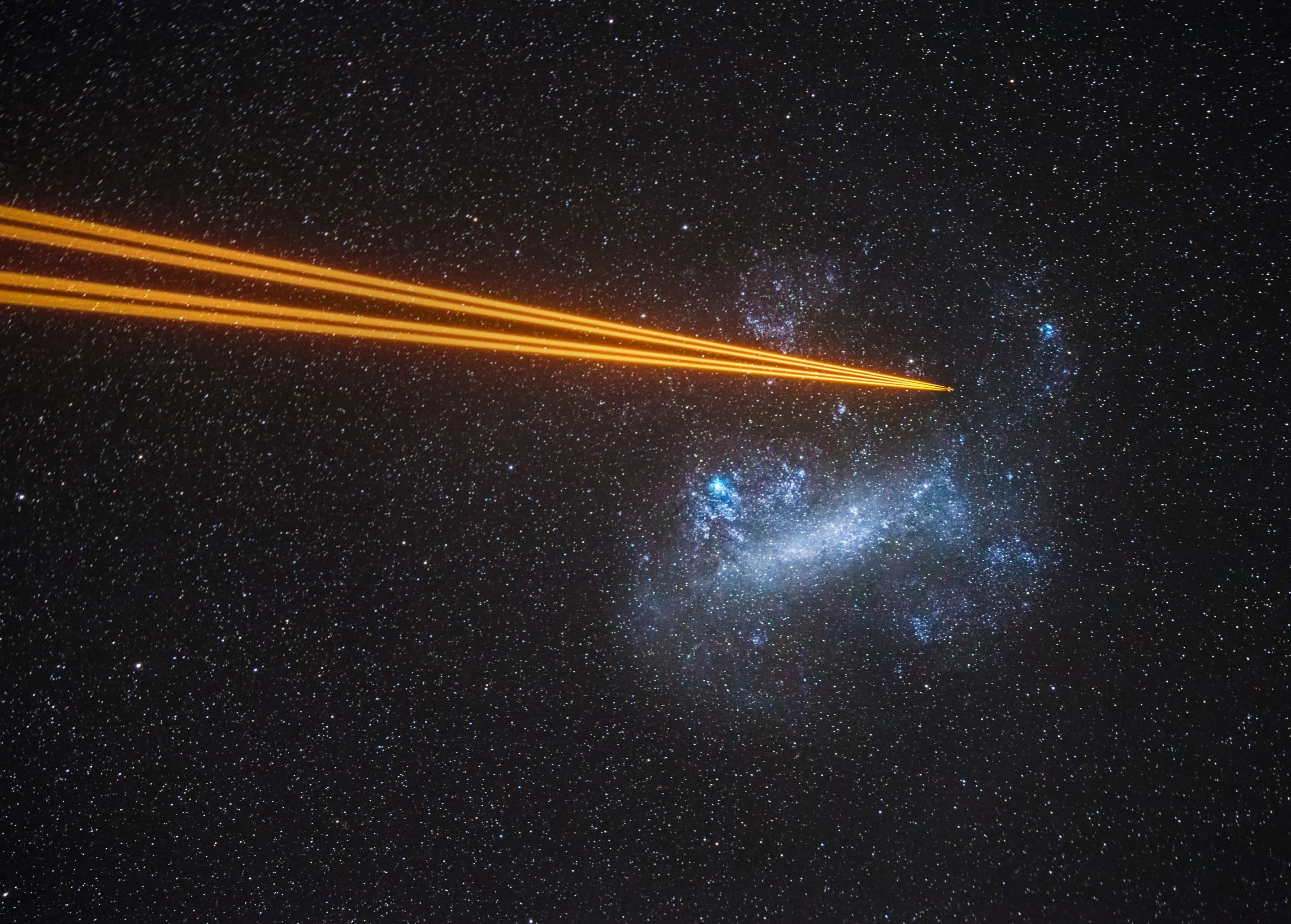 Highly Commended - Galaxies. Attack on the Large Magellanic Cloud. Four lasers from one of the telescopes at Paranal Observatory pointing towards a globular cluster in the Large Magellanic Cloud. The lasers excite sodium atoms located in a layer about 80–90 km above the ground