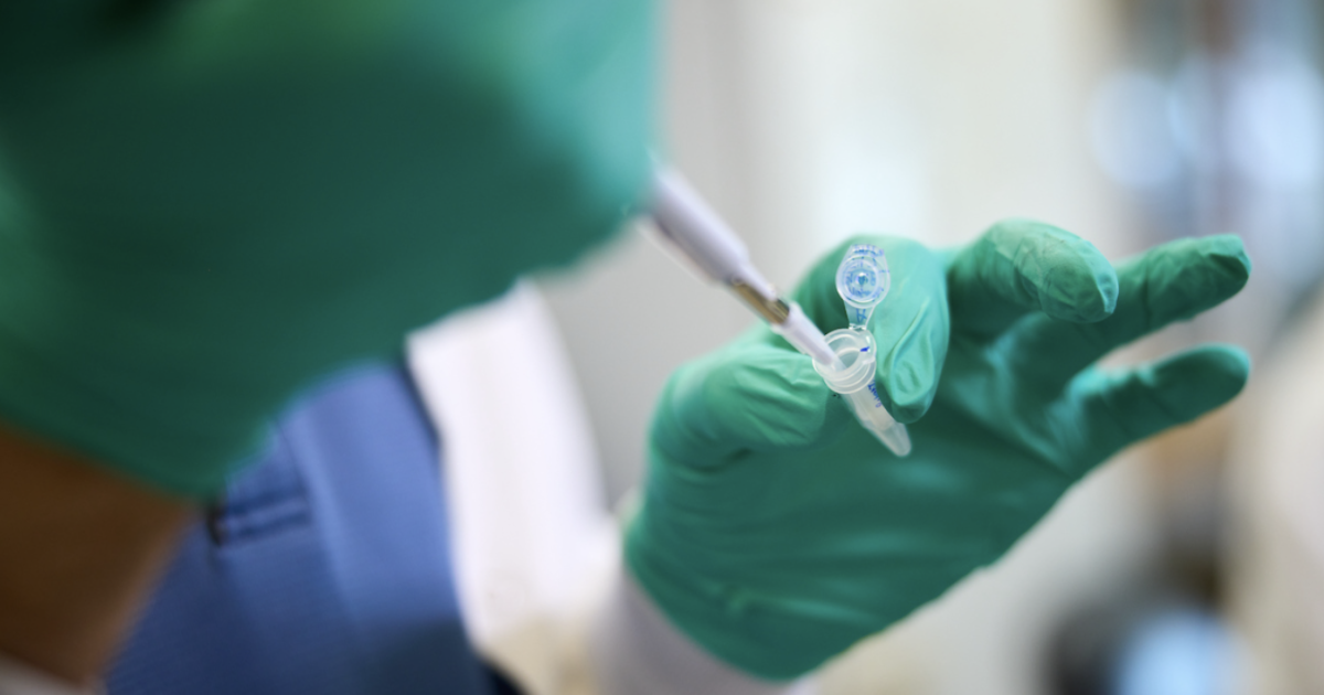 A medical professional drawing blood from a patient's arm in a clinical setting.