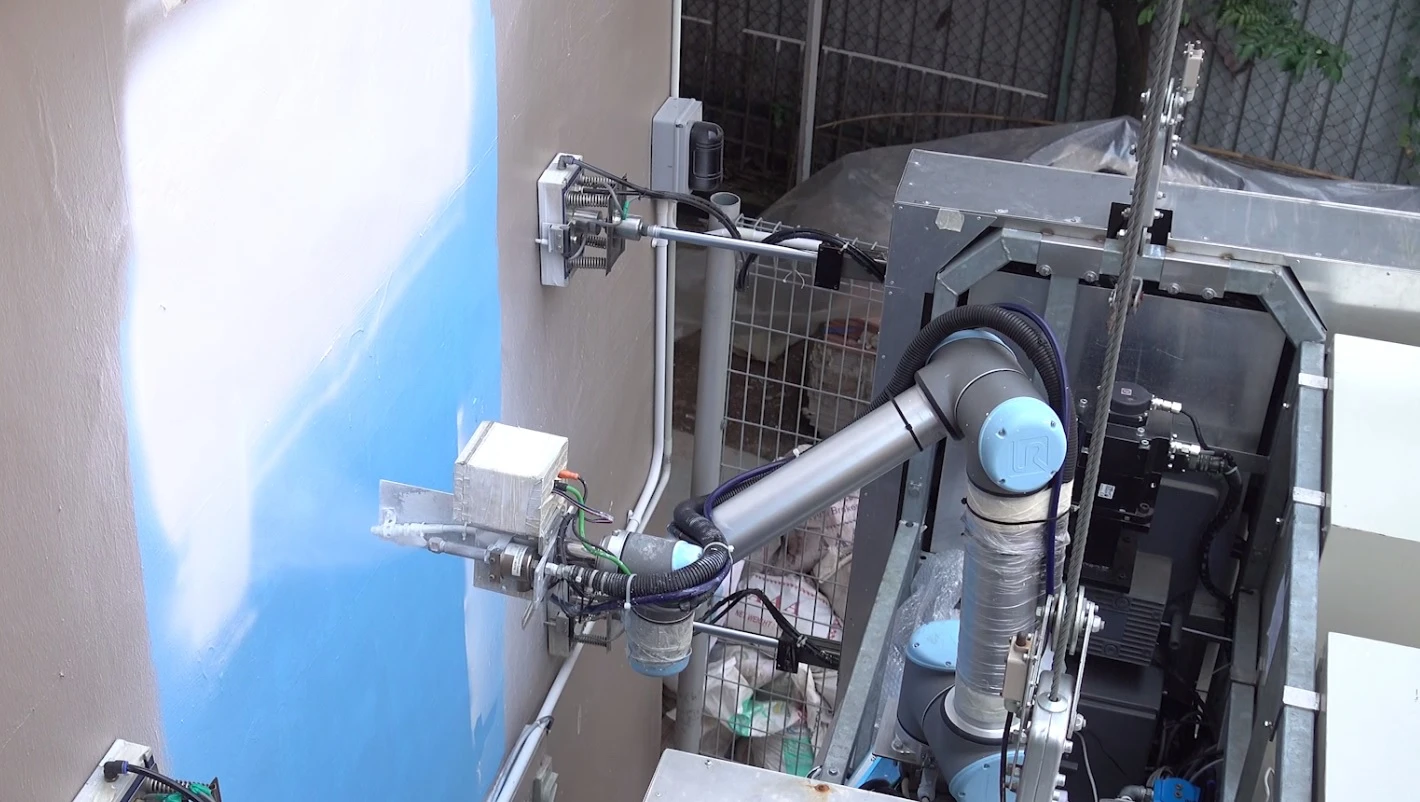 OutoBot applies white paint to an industrial building
