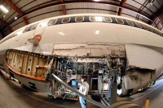 Sandian Kevin Howard inspects electrical wiring in the wheel well of a retired Boeing 727 at Sandia’s FAA Airworthiness Assurance NDI Validation Center. The wing on the 727 has been removed. (Photo by Randy Montoya)