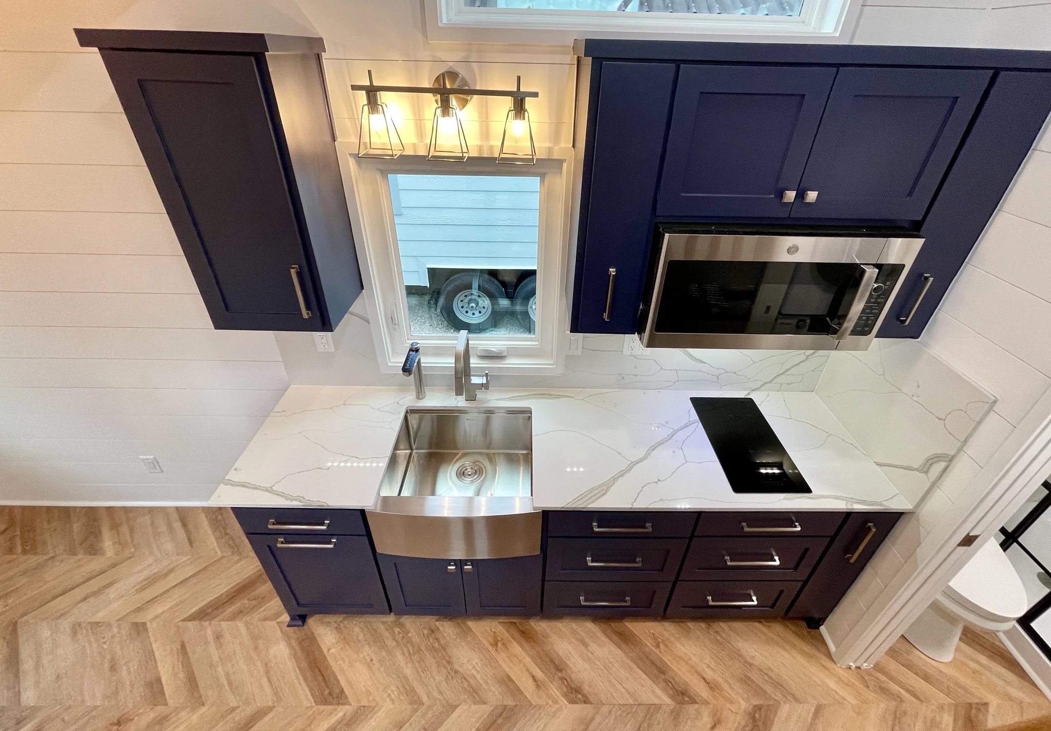 The Lady Bird's kitchen includes a sink, electric cooktop, a full-size fridge/freezer, and a combination microwave/convection oven and air fryer