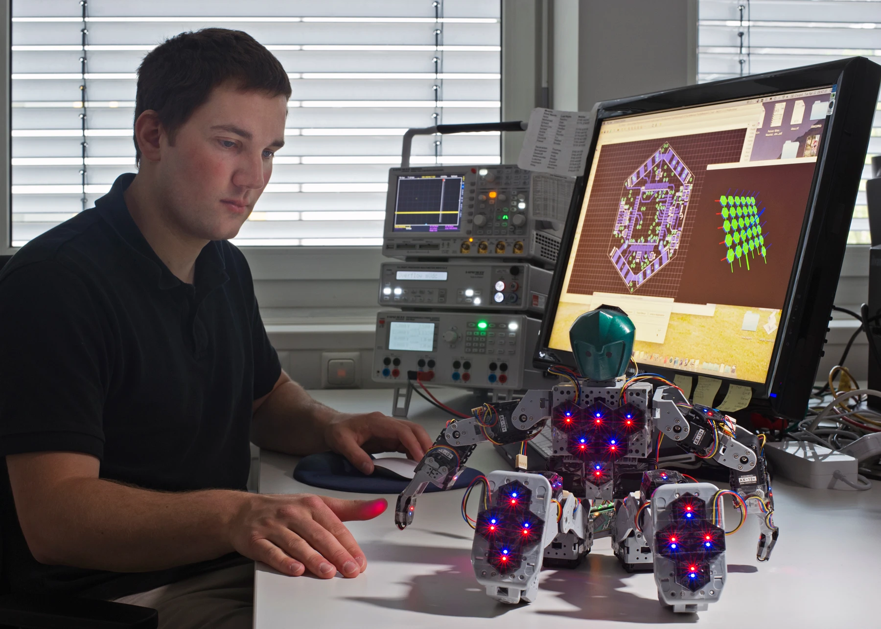 Engineer Philip Mittendorfer with the Bioloid Robot with 31 hexagonal sensor modules distributed throughout its body (Image: Andreas Heddergott / TU Munich)