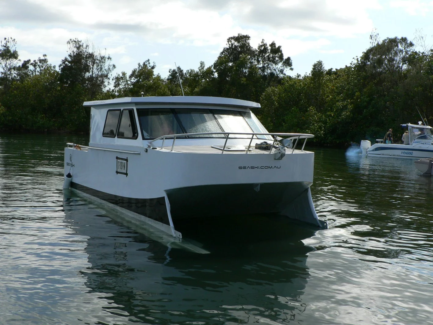 The 7-m (23-ft) vessel with its skis submerged at slow speed or moored at Fingal Boat Harbour, Northern New South Wales, Australia – it has a very wide beam at 3 m (9.8 ft)