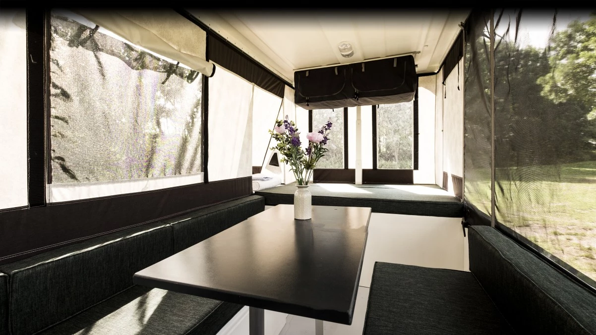 The interior is simple but roomy, with a wraparound sofa, dining table, lounge/bed, storage cabinet and under-bed kitchen access
