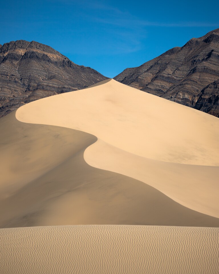 A snaking dune in Death Valley meets the saddle of the surrounding mountains