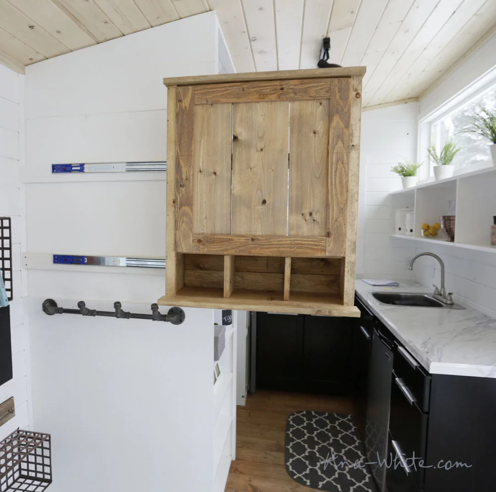 This storage cabinet in the Open Concept Rustic Modern Tiny House's main living area slides for easier access from the kitchen