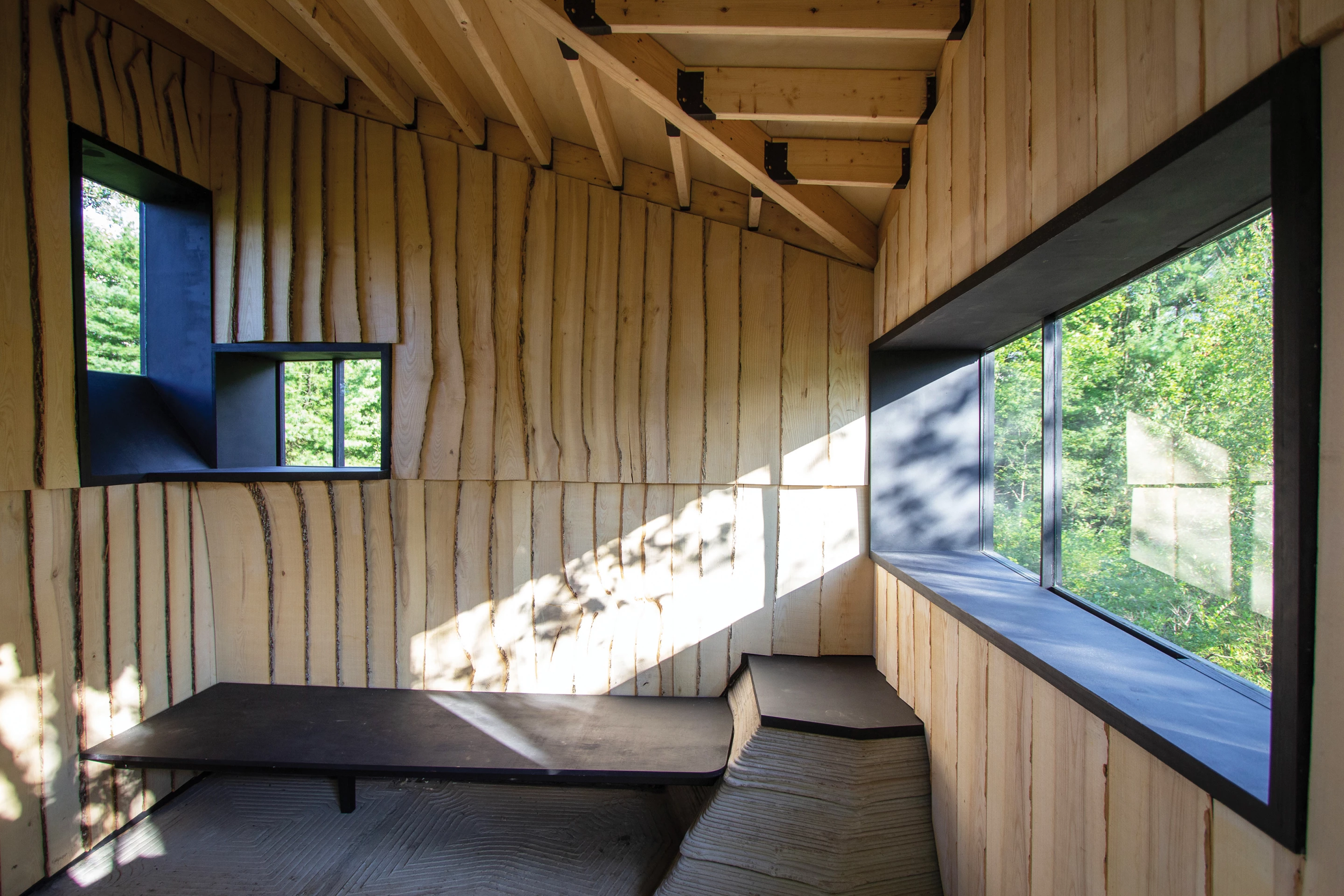 Ashen Cabin's interior is a simple one-room space that includes an area to sit, a sink, some shelving, and a fireplace with chimney