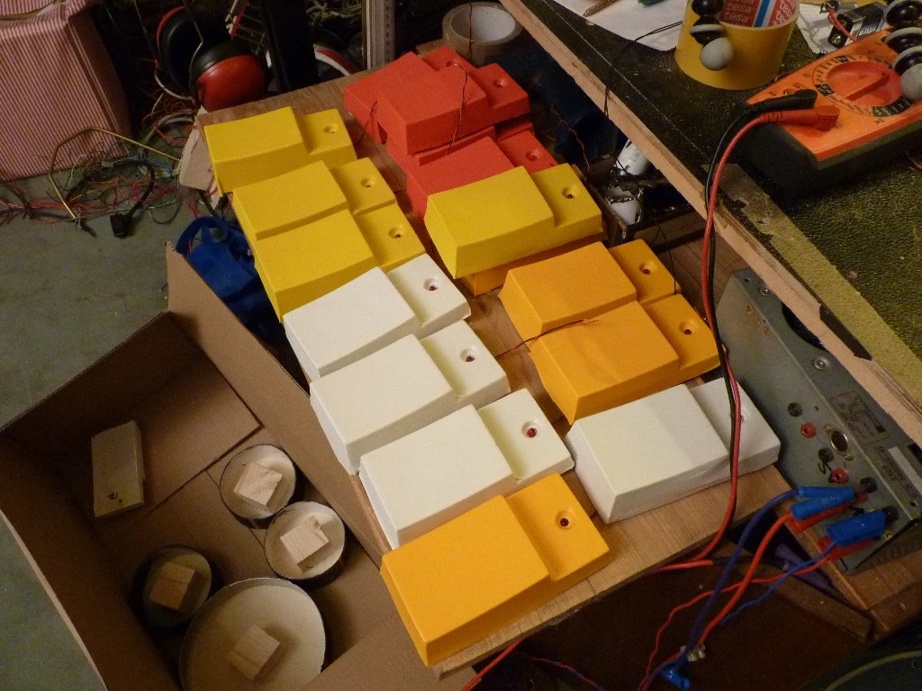 16 thermoformed buttons awaiting placement along the bottom of the frame