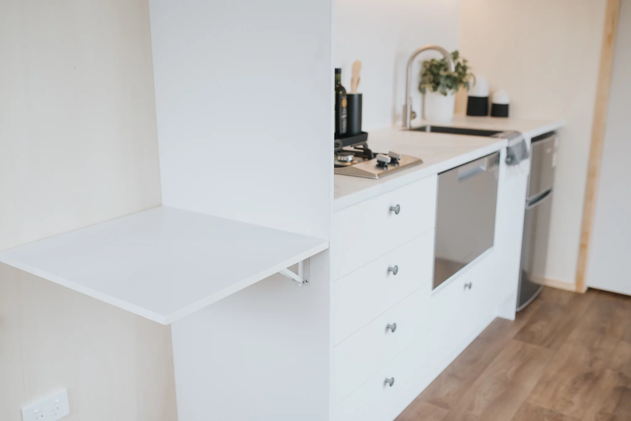 The Te Whare Nukunuku Tiny House's kitchen features a small drop-down table