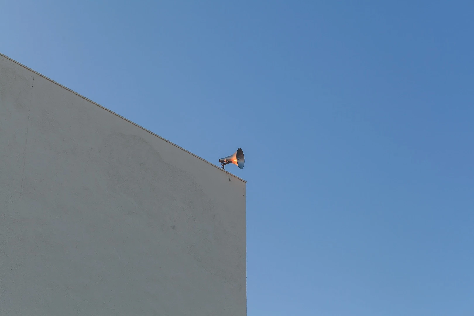 We really like raset's clean minimalist photo of a concrete building and loudspeaker against the blue sky