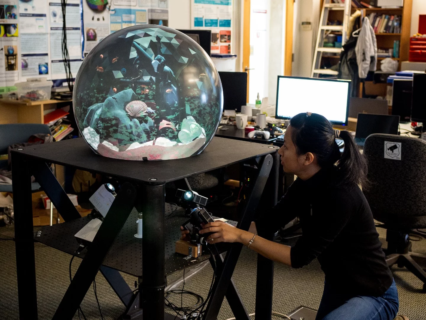 A member of the research team carefully positions one of four projectors that combine to create the spherical image