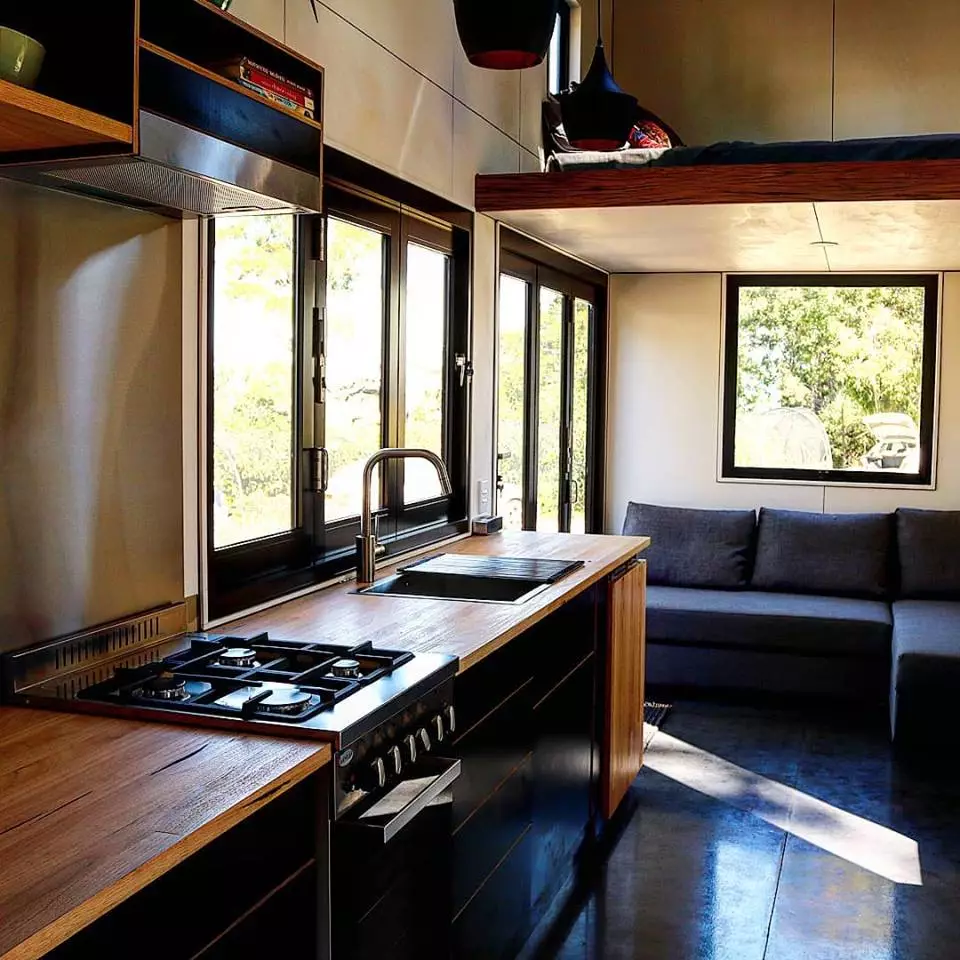 The Sowelo tiny house has a full size kitchen with stainless steel all gas stove and oven and full size energy-efficient fridge