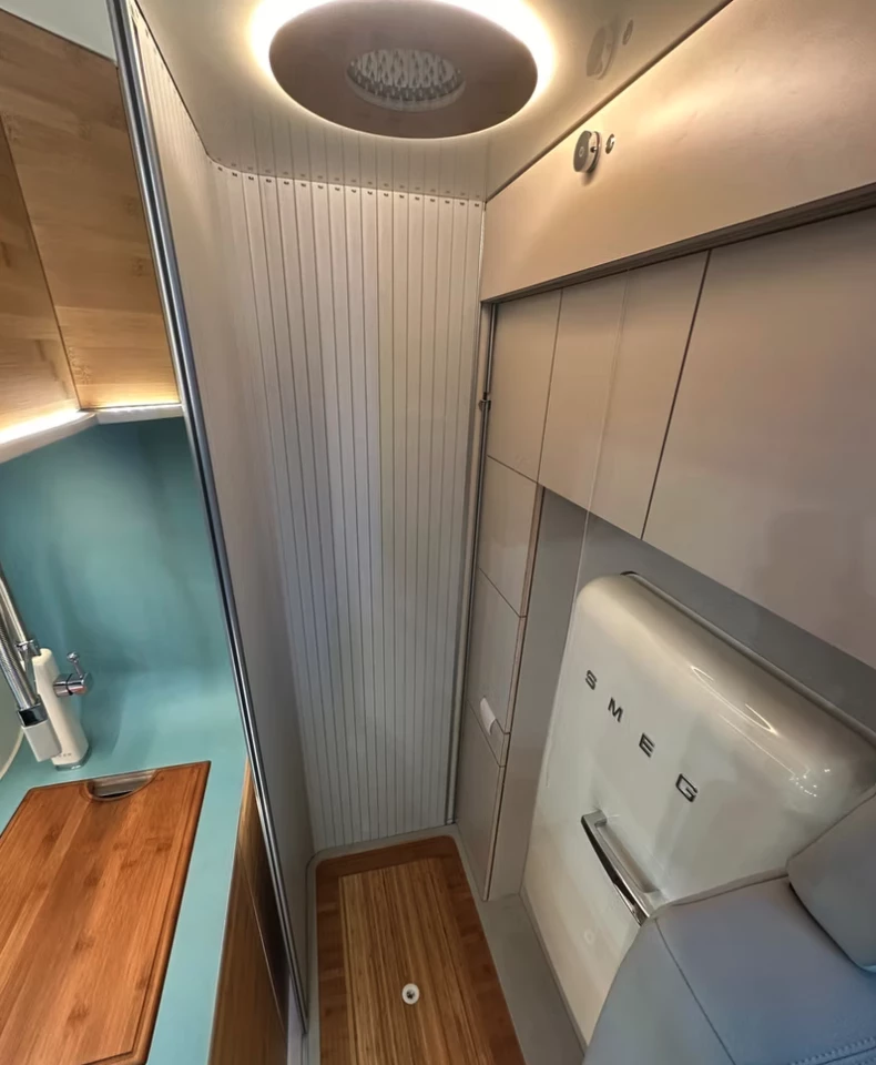 The bathroom roller door slides out from behind the cabinetry to create a private shower/toilet room; note the rainfall shower head located within the round ceiling light and the water control on the upper cabinet