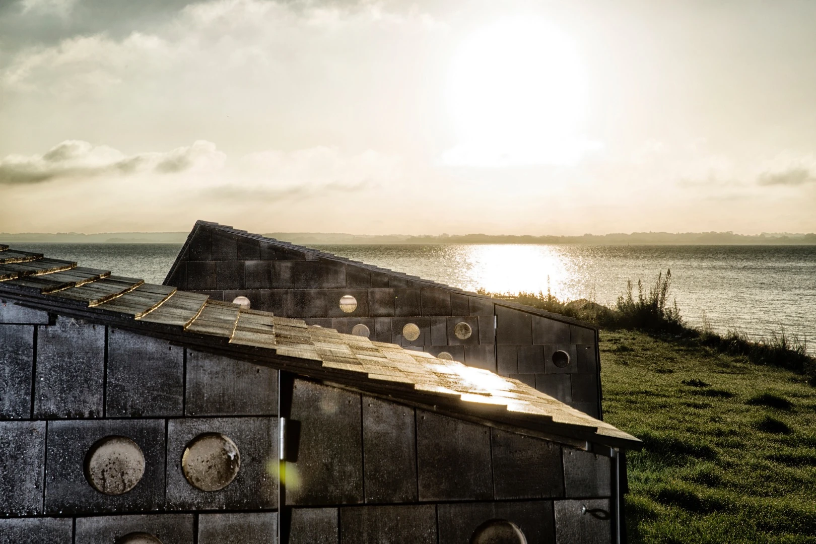 The exterior is clad in wood shingles treated in black tar oil, presumably to protect the structures against the tough northern coastal climate