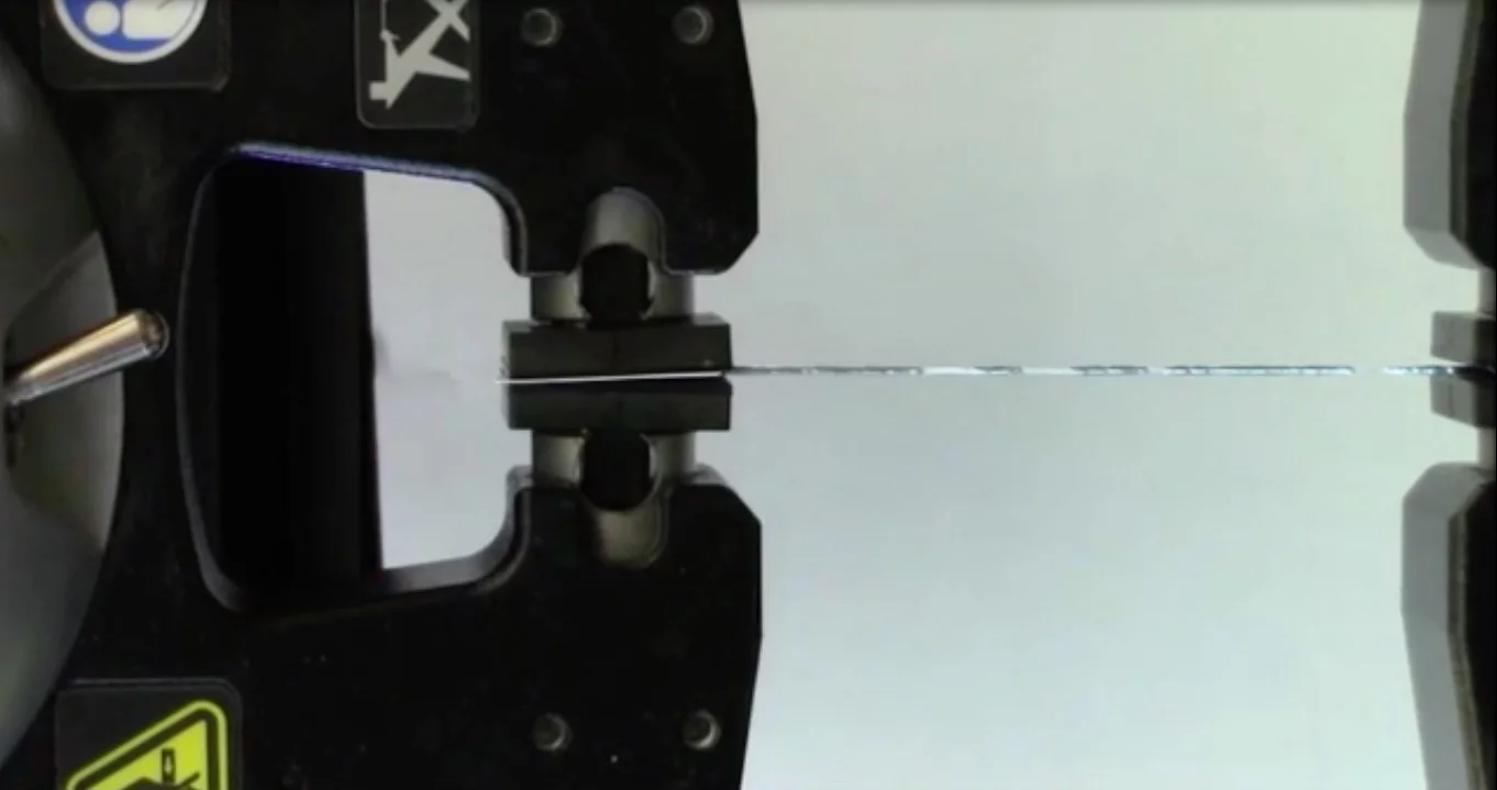 A sample of the fiber is stretched in the lab – the silver sections are the gallium core, which shows numerous breaks