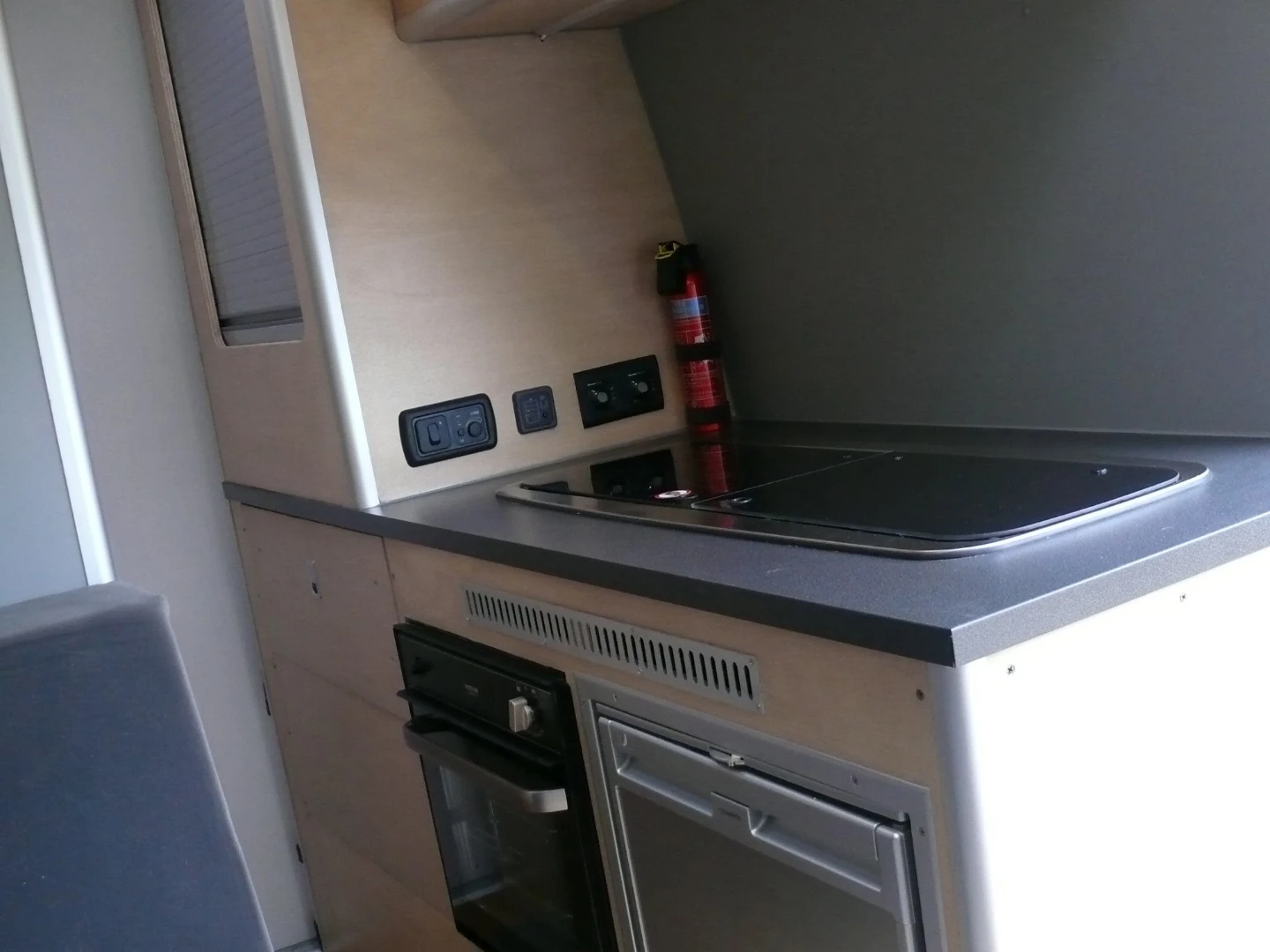 The kitchen area includes a dual-burner stove/sink combo, oven/grill and compressor fridge