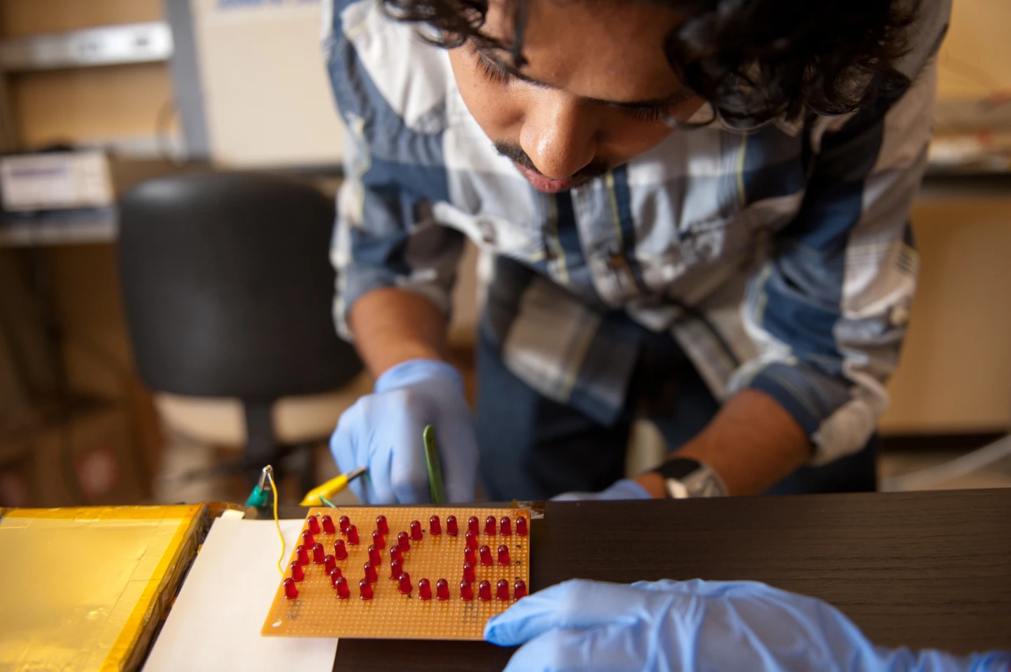Rice University graduate student Charudatta Galande wires an array of LEDs to a set of batteries painted on the surface of ceramic tiles (Photo: Jeff Fitlow/Rice University)