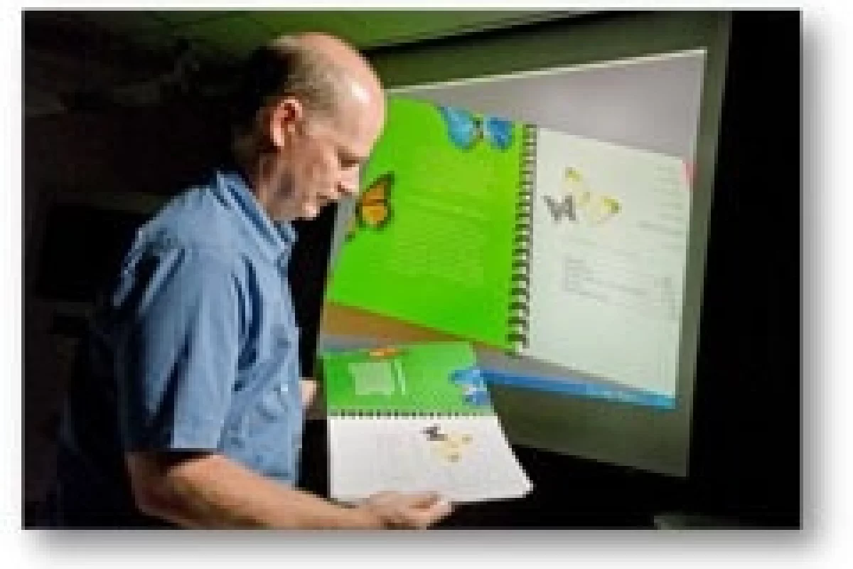 Xerox scientist Rob Rolleston looks over a finished document as Xerox's new 3D Document visualization software displays the document on the screen in the background. (Photo by John Griebsch)