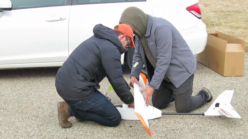 Research team members mount the battery wing on the drone
