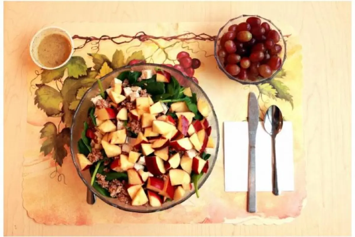 This image shows one of the study's unprocessed lunches, consisting of a spinach salad with chicken breast, apple slices, bulgur, and sunflower seeds and grapes