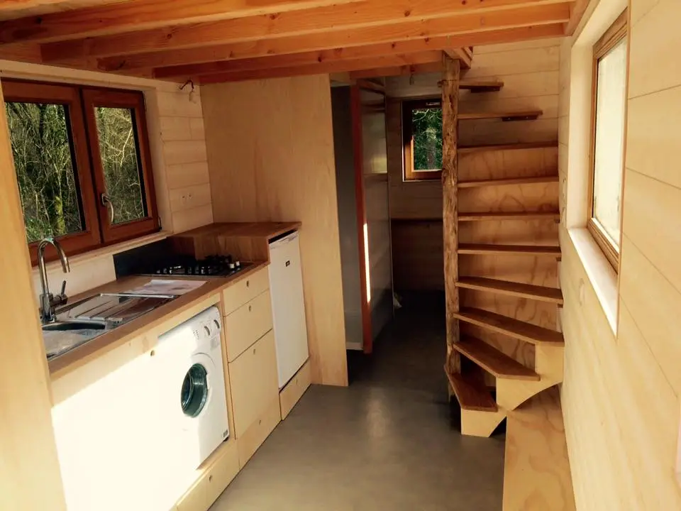 The kitchen includes stove, washing machine, refrigerator, and a long counter