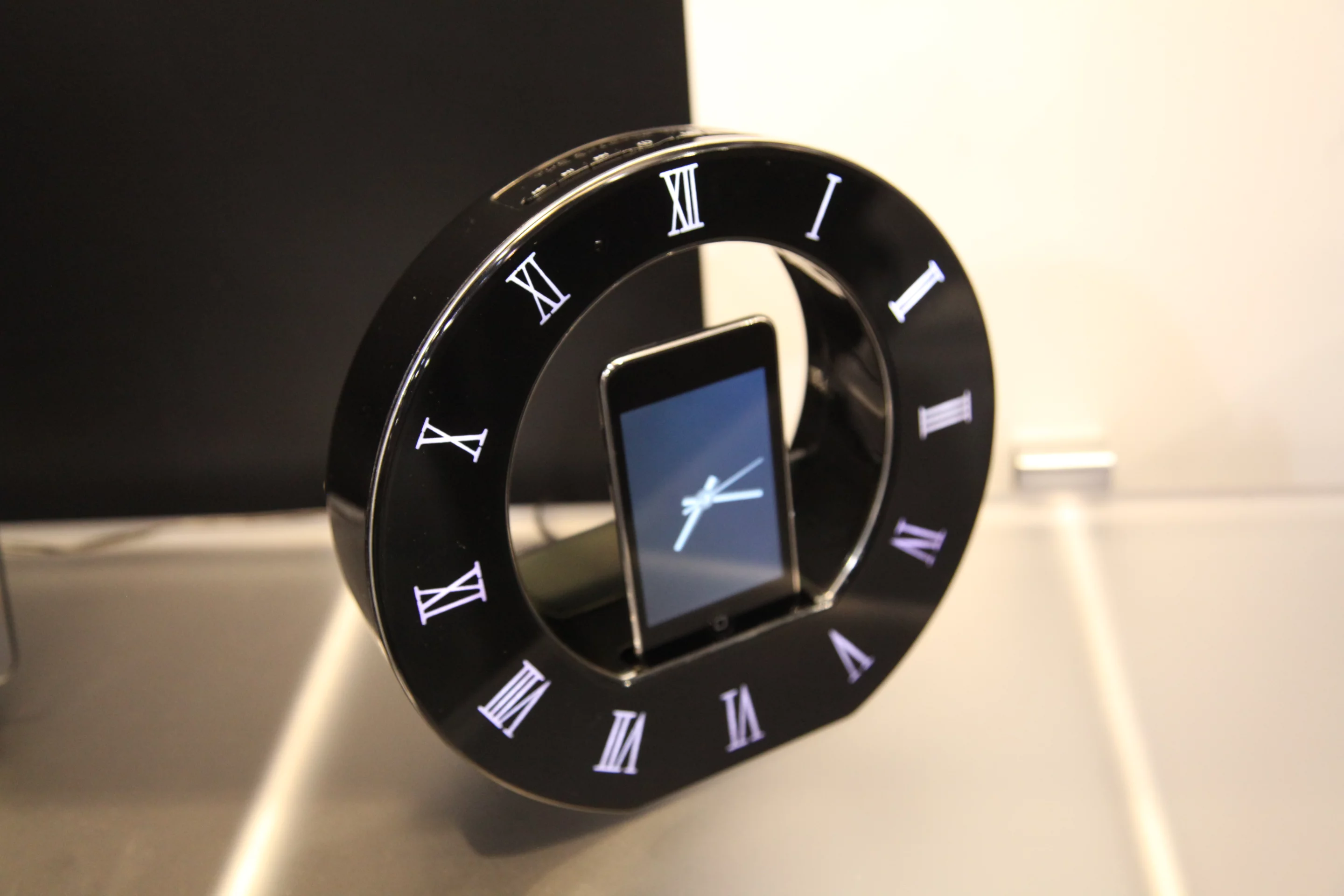 Roman numerals surround the docked device, the screen of which displays analog clock hands thanks to a free iTunes app