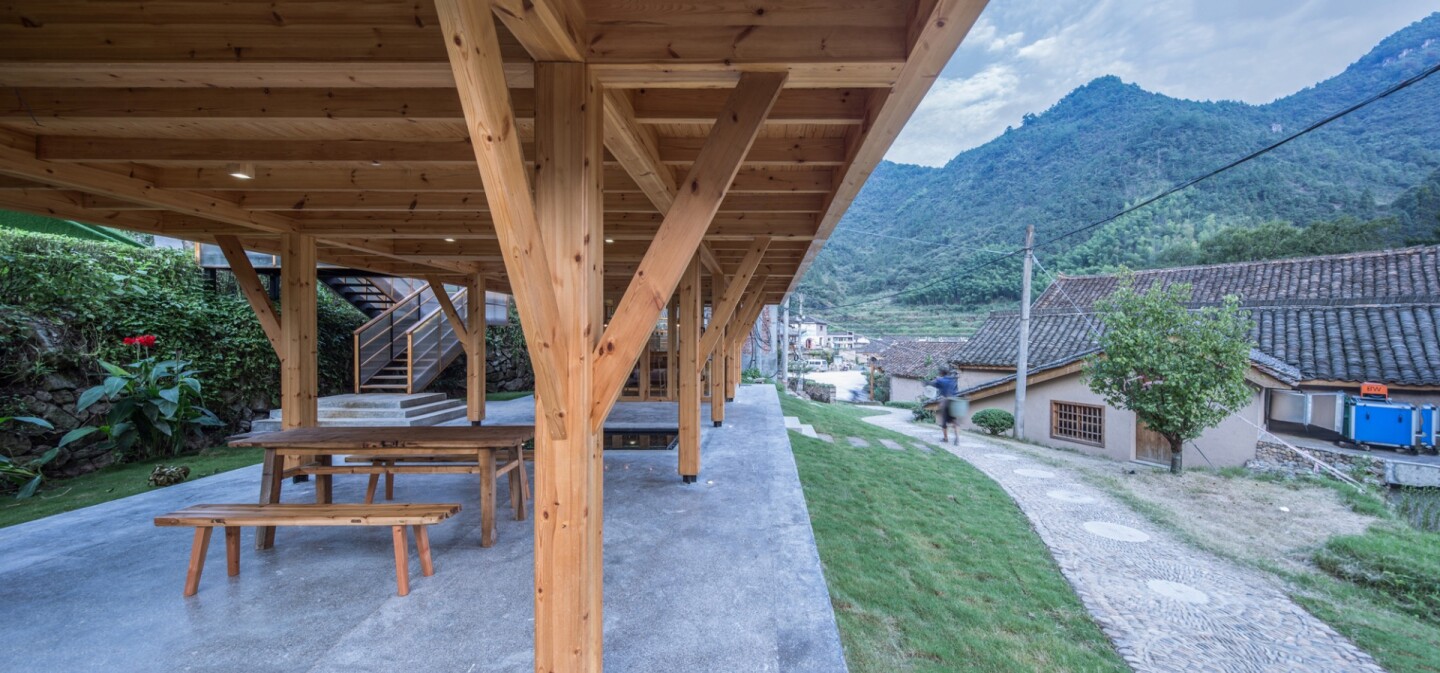 The Mountain House in Mist creates a covered semi-outdoor space beneath it that includes tables and chairs for villagers to sit and chat