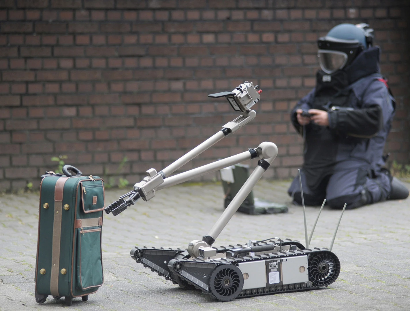 Emergency personnel defuse a suitcase bomb with the robot's aid