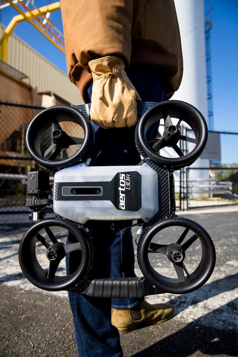 The Aertos 130IR features a carbon fiber composite frame with grip tape-wrapped carrying handles, protective shrouds around its four propellers, and an omnidirectional array of nine sensors