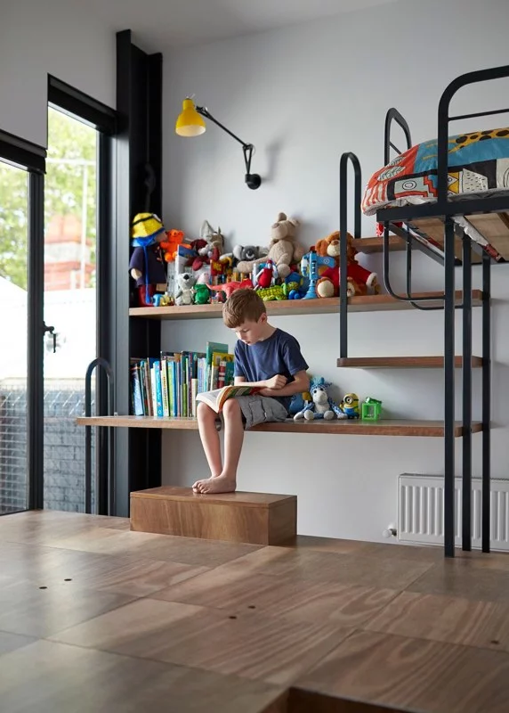 The child's bedroom features a desk that doubles as seating and forms part of the shelving/steps up to the bed