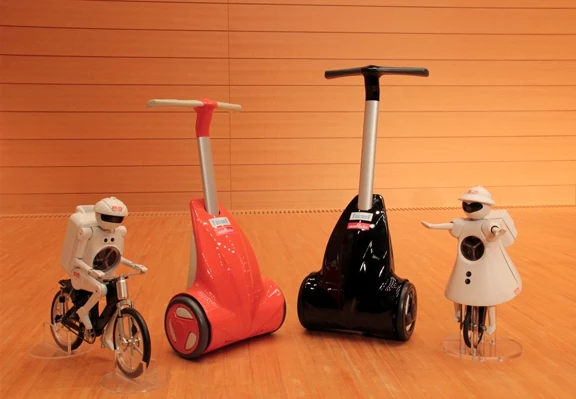 Murata Manufacturing's KeePace, a walk-assist device for the elderly or disabled, stands next to the company's mascot robots.