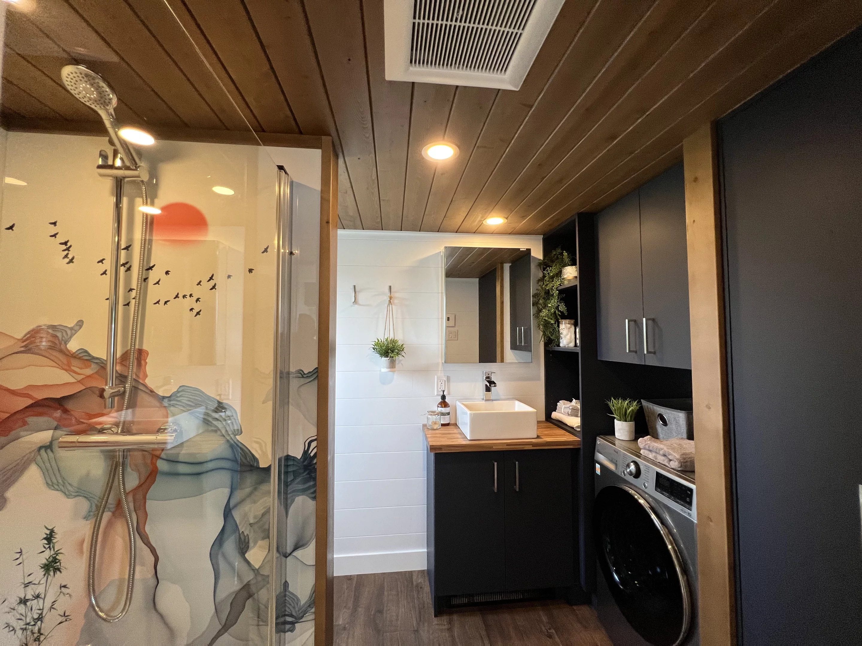 The Thuya 10 x 26's bathroom includes a shower, vanity sink, composting toilet, and a washer/dryer