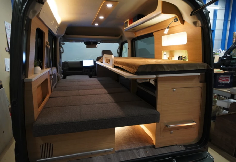 The Oka Miniature Cruise Cozy has a unique bunk bed layout that uses the kitchen as a sleeping platform