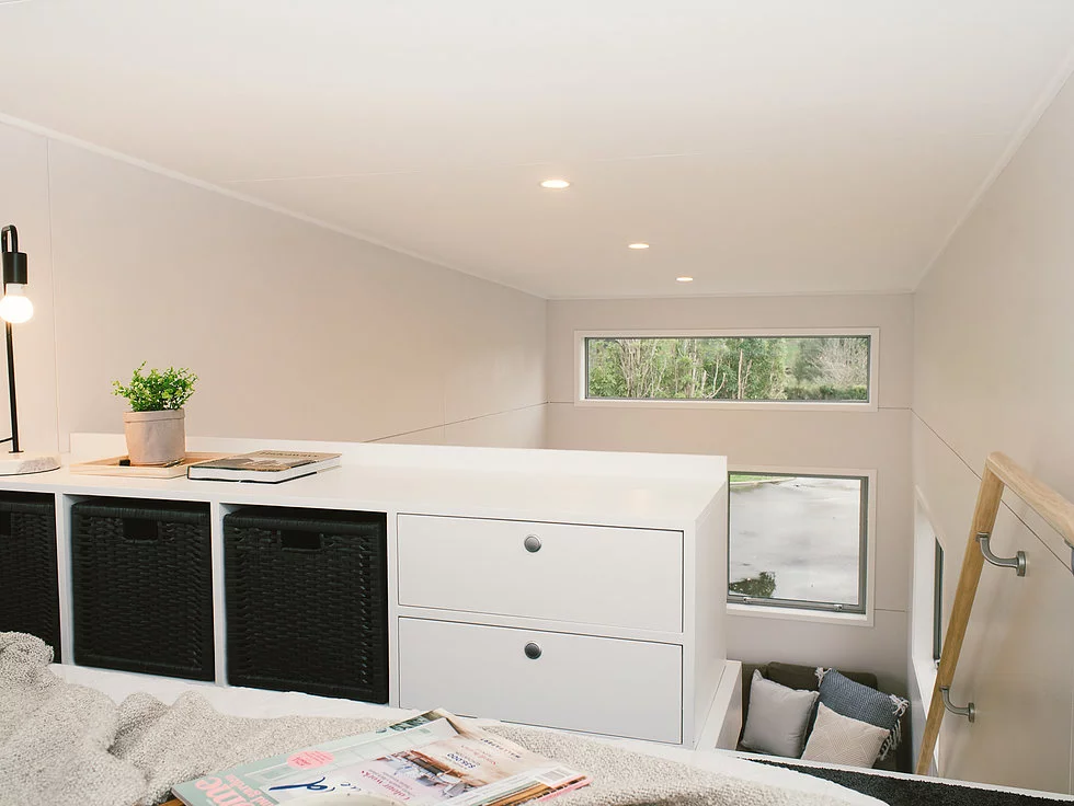 The Buster Tiny House's loft bedroom has integrated storage space