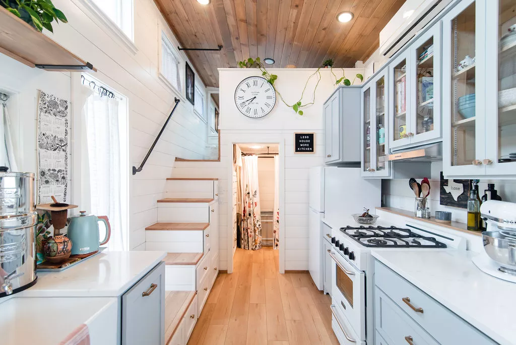 The kitchen in Jen’s 34' x 10' Tiny Home contains an oven with four-burner propane-powered stove, sink, fridge/freezer