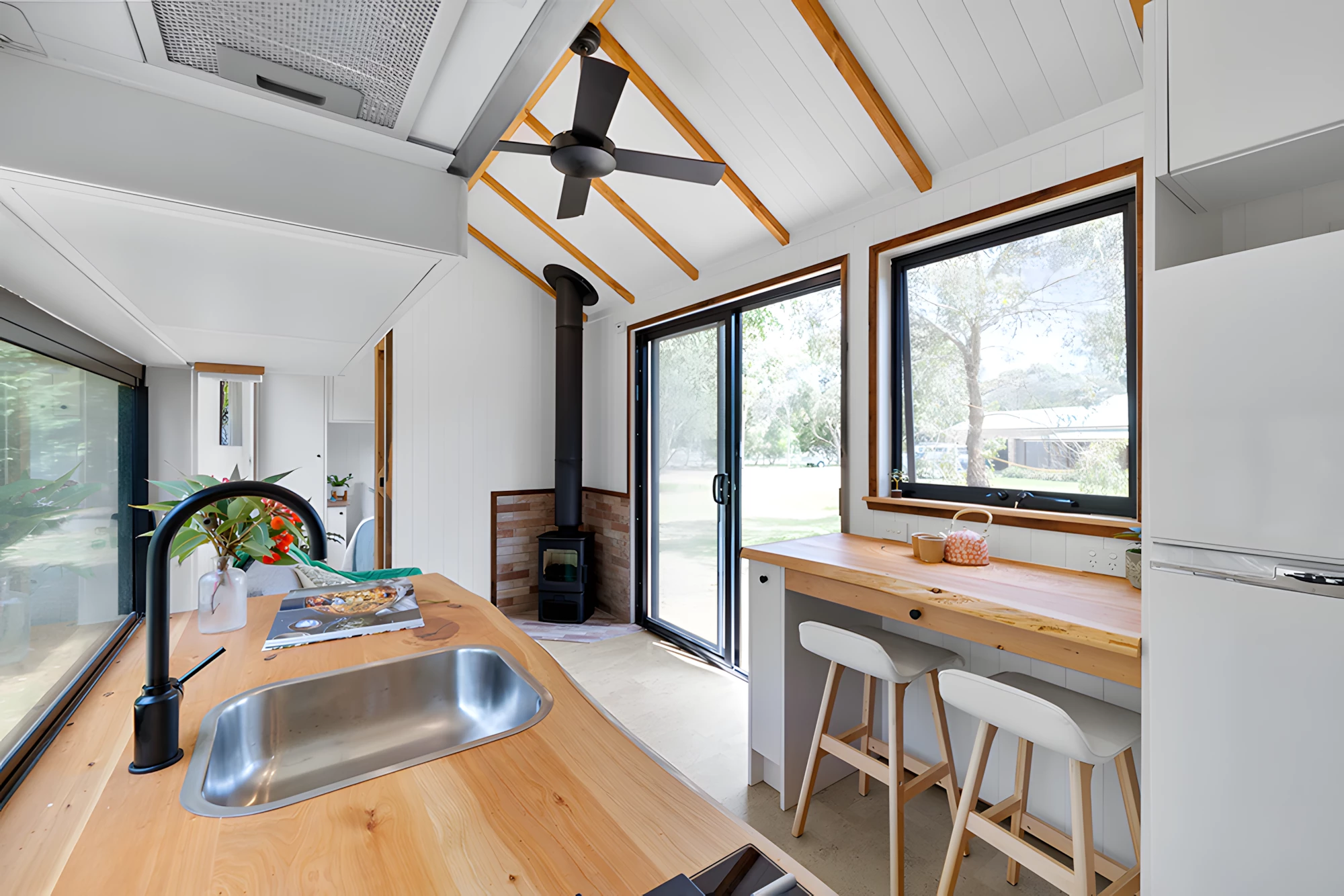 The Casuarina's living room includes a wood-burning stove and a ceiling fan