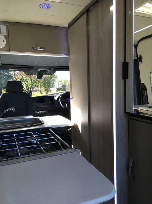 The kitchen area includes a three-burner stove and sink