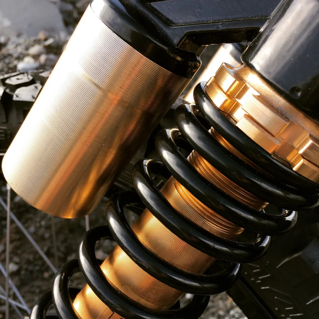 Close up of the Suru Scrambler's gold anodized reservoir shocks