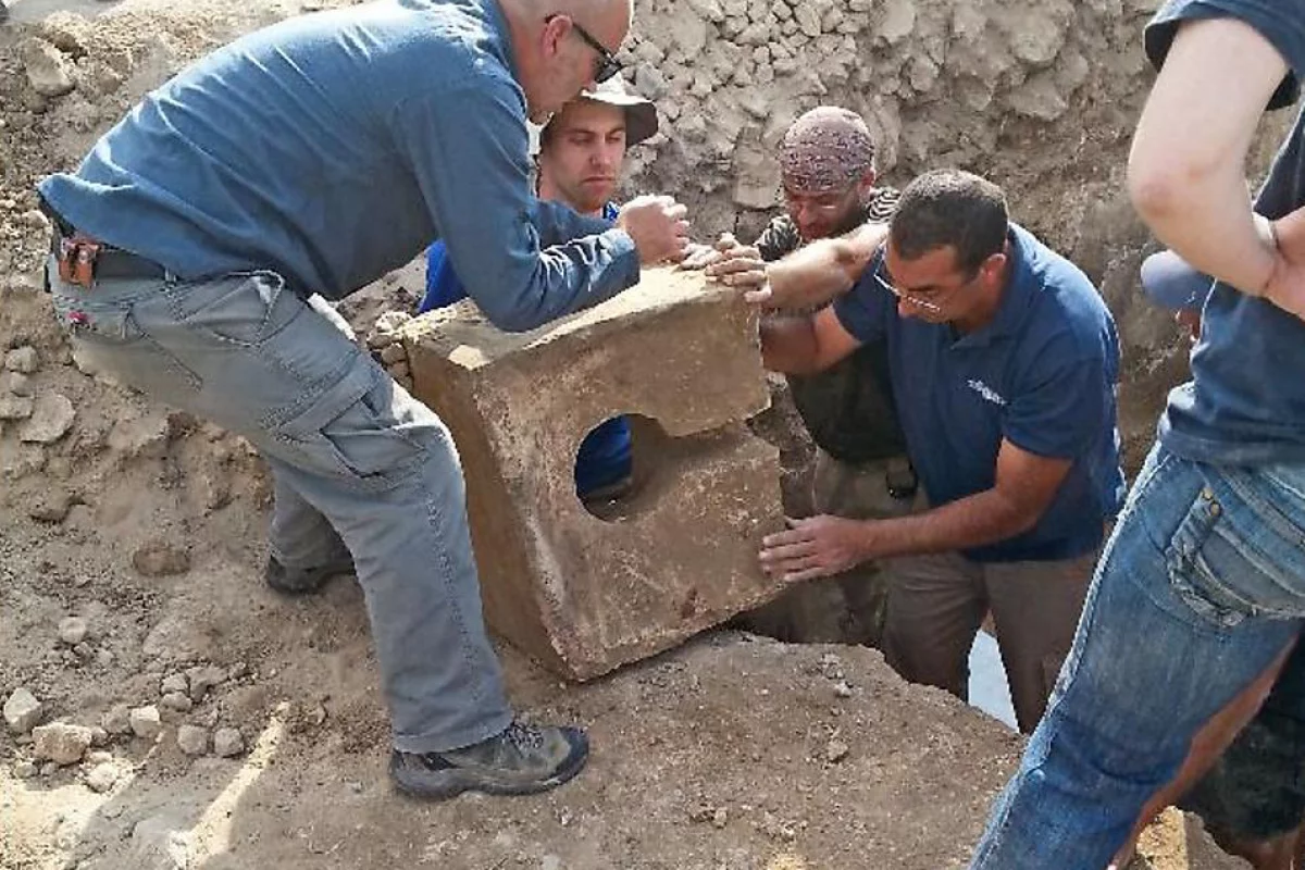 Archaeologists unearthing a stone toilet from a gate shrine at Tel Lachish, Israel