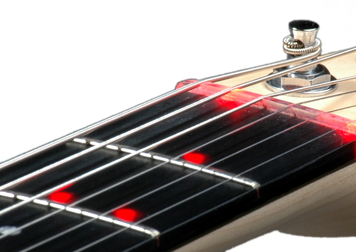 There's a light strip at the nut to indicate open string prompts and an LED under each string at 21 of the 22 fret positions along the neck