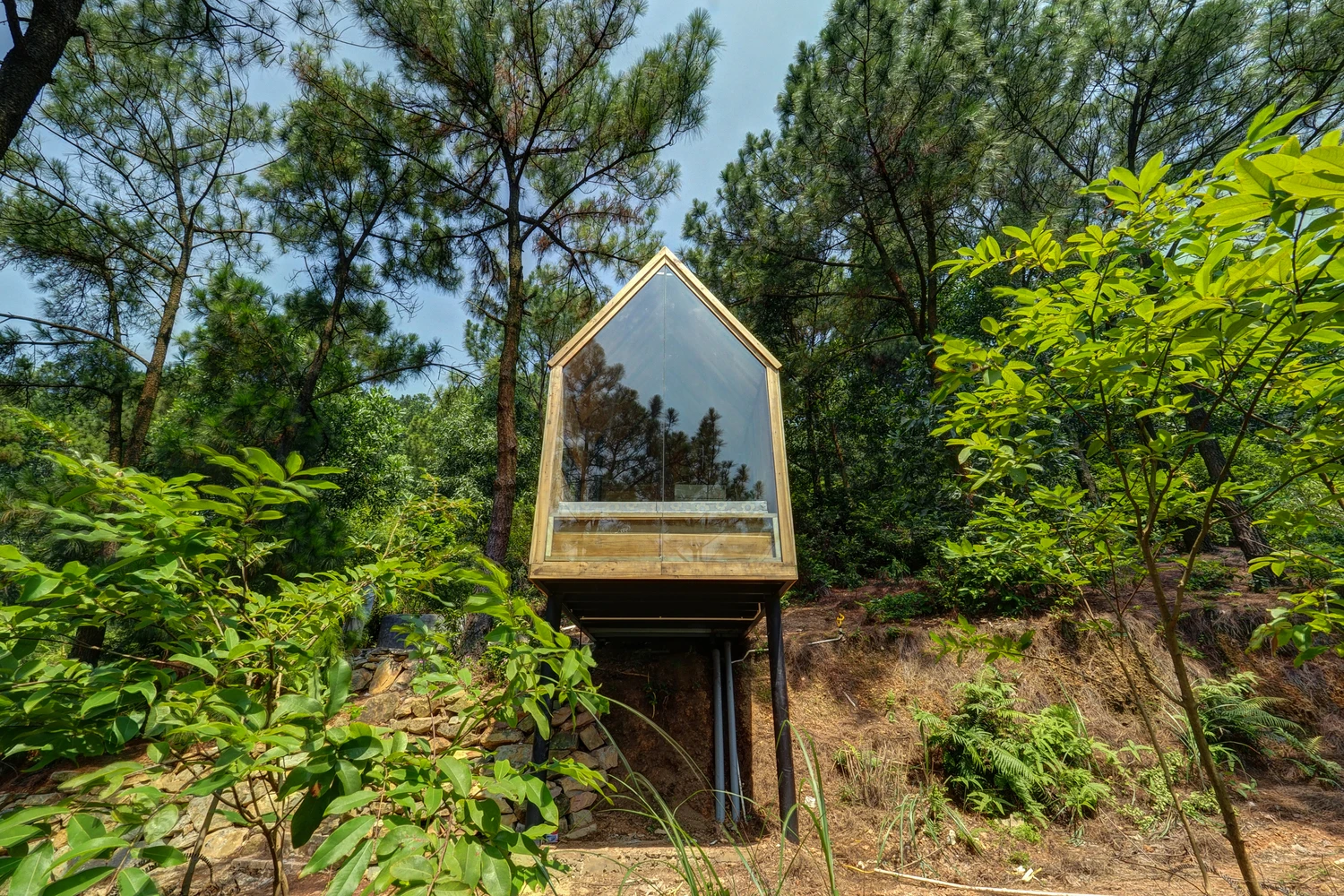 The cabin features a large floor-to-ceiling glass wall at the front ofthe home, capitalizing on its surrounding views and lush setting