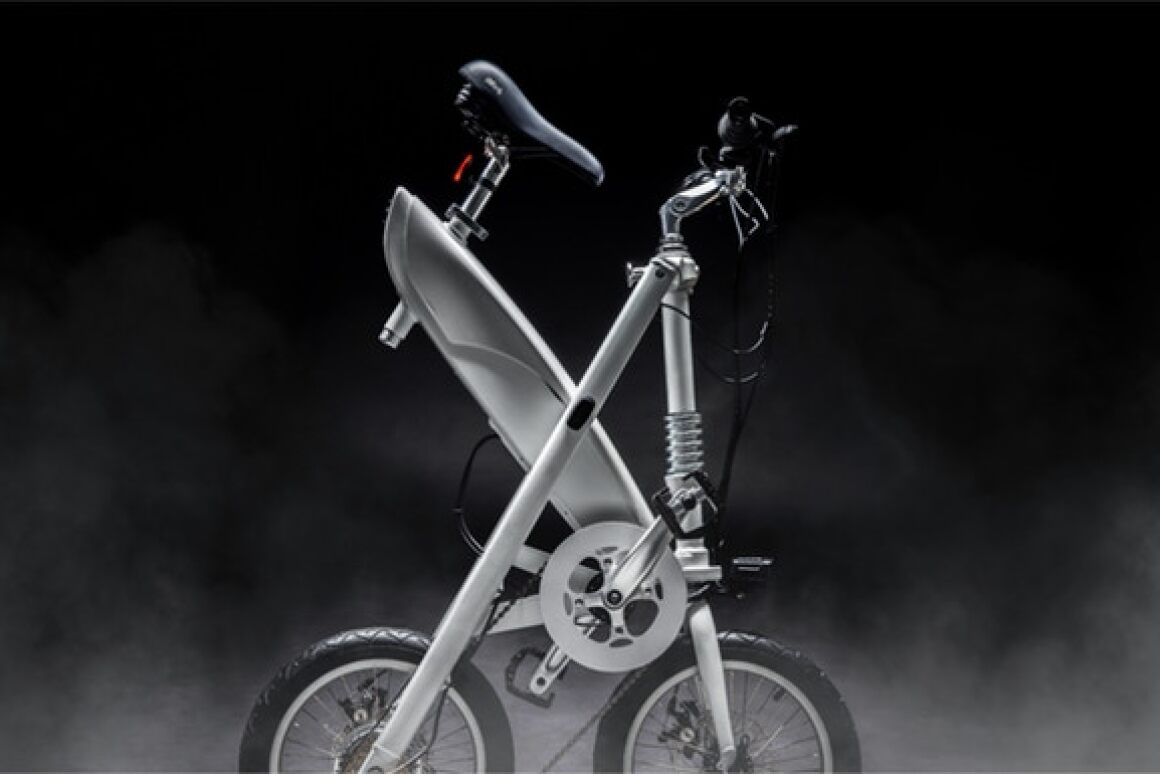 The folding point is at the center of the frame, with the rider pulling on a central knob and lifting up to fold