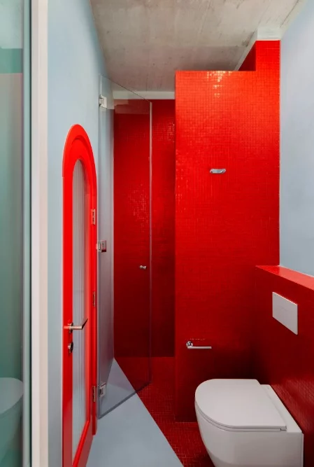 The compact bathroom is finished in red glass mosaic, turning it into a fun light-filled chamber
